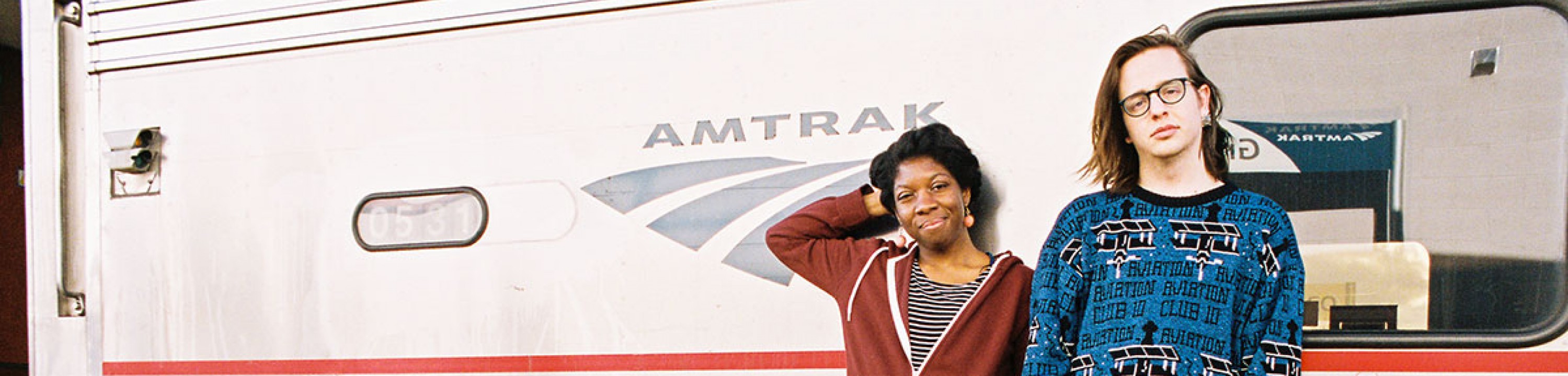 Two students pose in front of the Amtrak.
