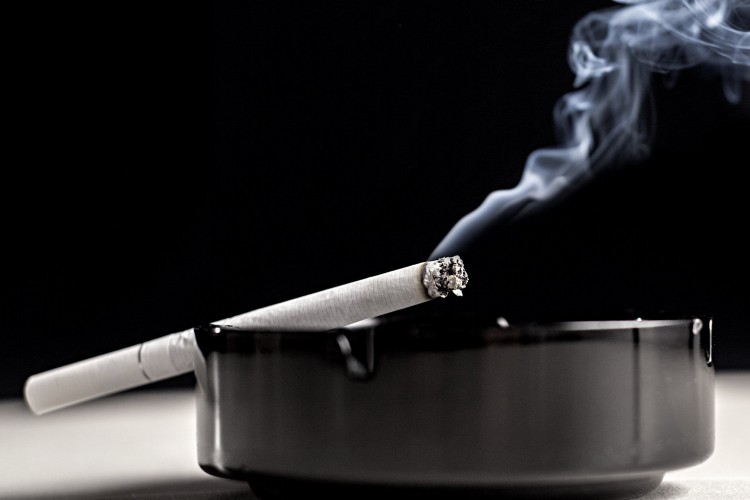 A cigarette burns in an ashtray